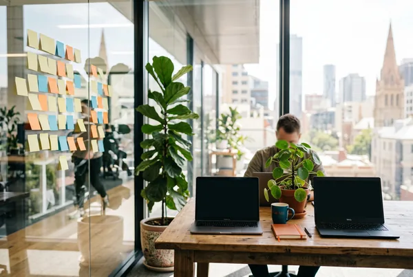 A startup founder working at a desk with a laptop and notebook in an early-stage office